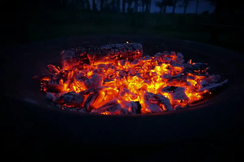 A fire pit full of glowing coals at dusk